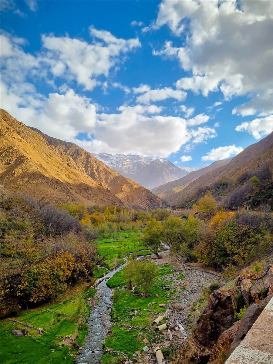 Green Imlil valley river with snow-capped Toubkal peaks, High Atlas Morocco